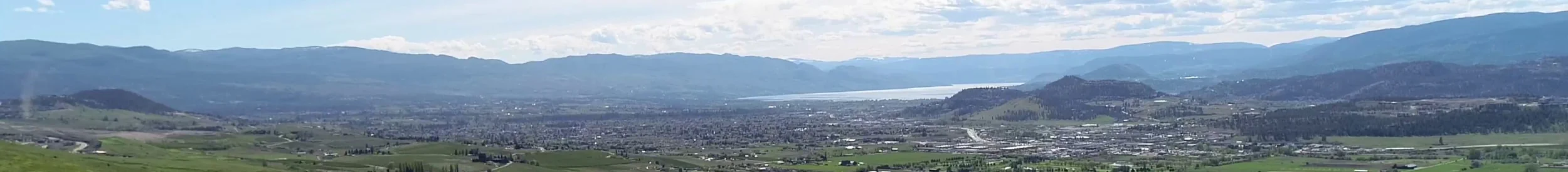 A panoramic view of the Okanagan Valley with West Kelowna in the foreground and mountains in the background